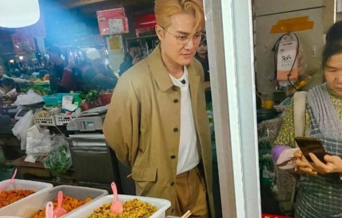 吴克群现身贵州遵义菜市场买菜，穿大衣外套，一头黄发，打扮时尚