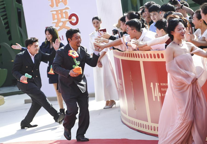   4月18日，电影《末路狂花钱》演员贾冰（左三）等与观众在第十四届北京国际电影节开幕红毯上互动。新华社记者 陈钟昊 摄